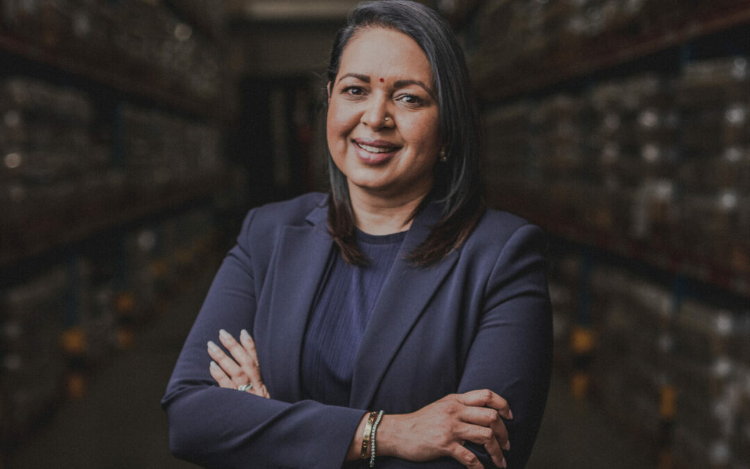 Photo of businesswoman in black suit standing with arms folded and smiling