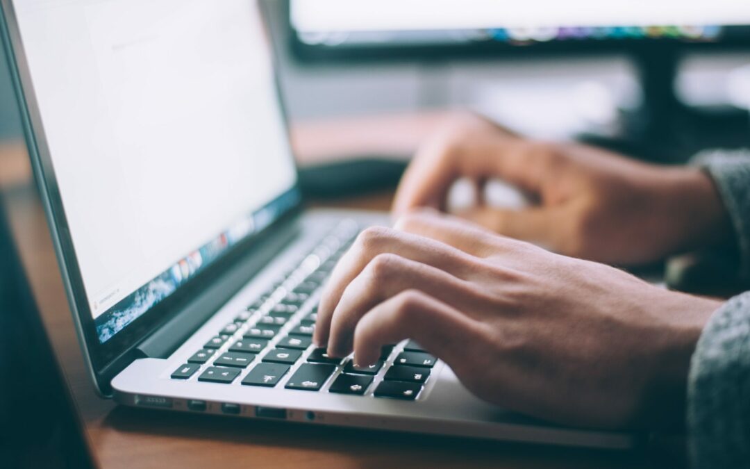 Closeup photo of a man's hands as he types on a laptop